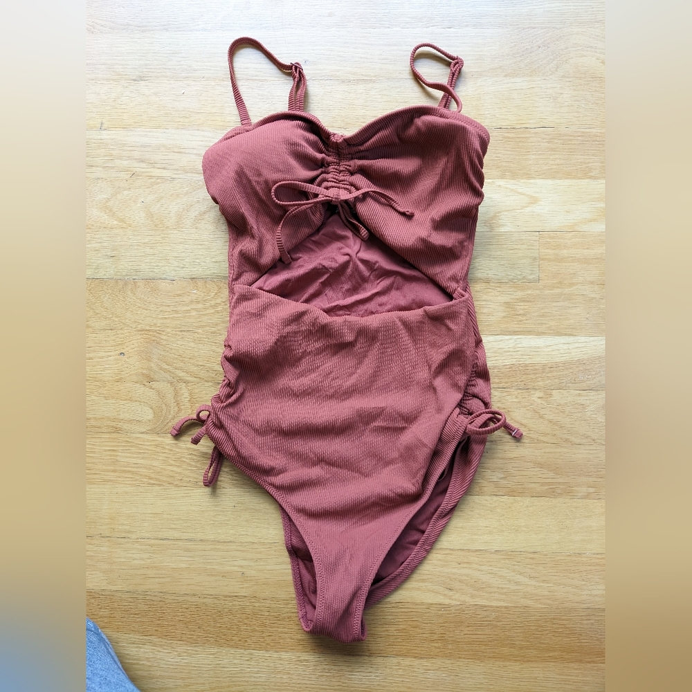 Rust orange one piece bathing suit. Front cutout. Adjustable straps. Size Medium